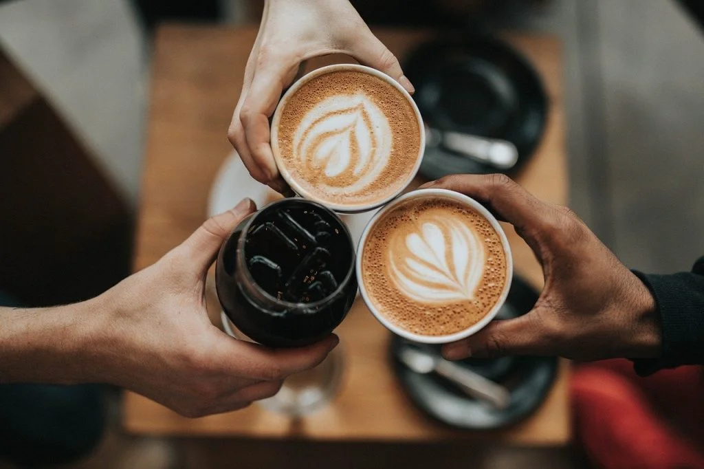 Tomar un café con amigos. Tres manos con bebidas