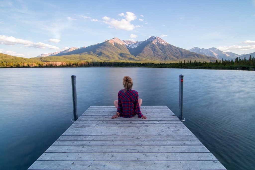 Consciencia plena. Mujer contemplando un lindo y tranquilo paisaje. Lago y montañas