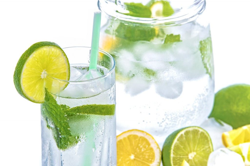 Hábitos saludables. Beber agua fresca con hielo, rodajas de limón y hojas de hierbabuena